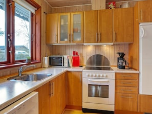 Una cocina compacta con armarios de madera, un microondas, una estufa y un refrigerador.
