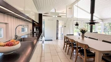 A modern kitchen with a central island, a dining area with wooden chairs, and a large window providing natural light.