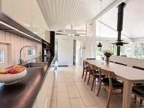A modern kitchen with a central island, a dining area with wooden chairs, and a large window providing natural light.