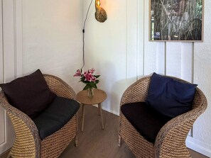 Two wicker chairs with dark cushions, a small wooden table with a vase of flowers, and a wall-mounted light fixture. - 12 Person Holiday Home in Fano (Fano)