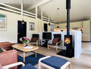 Ett mysigt vardagsrum med en öppen spis, bekväma sittplatser och en tv.