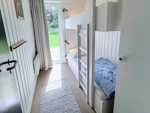 A room with bunk beds, a door with a handle, a window, and a view of greenery outside. - 12 Person Holiday Home in Fano (Fano)