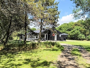 A modern building with a covered outdoor seating area, surrounded by lush greenery.