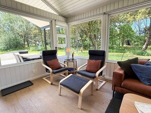 A sunroom with two chairs, a bench, and a sofa.