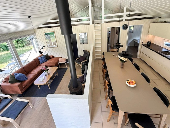 A modern interior with a dining area, kitchen, and a large window overlooking a garden.