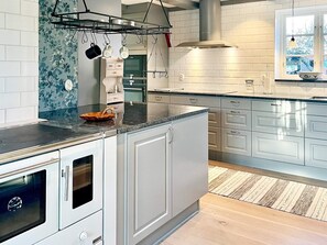 A modern kitchen with white cabinets, a black countertop, and a wooden floor.