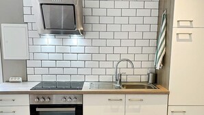 A modern kitchen with white cabinetry, a stainless steel range hood, a built-in oven, and a sink. - 4 Star Holiday Home in Farlov (Färlöv)