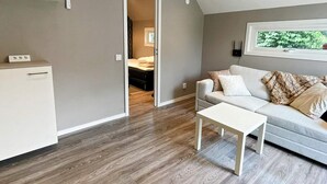 A compact living space with a kitchenette, a sofa, a coffee table, and a window with a view of greenery. - 4 Star Holiday Home in Farlov (Färlöv)