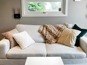 A light-colored sofa with a white cushion and a patterned throw blanket. - 4 Star Holiday Home in Farlov (Färlöv)