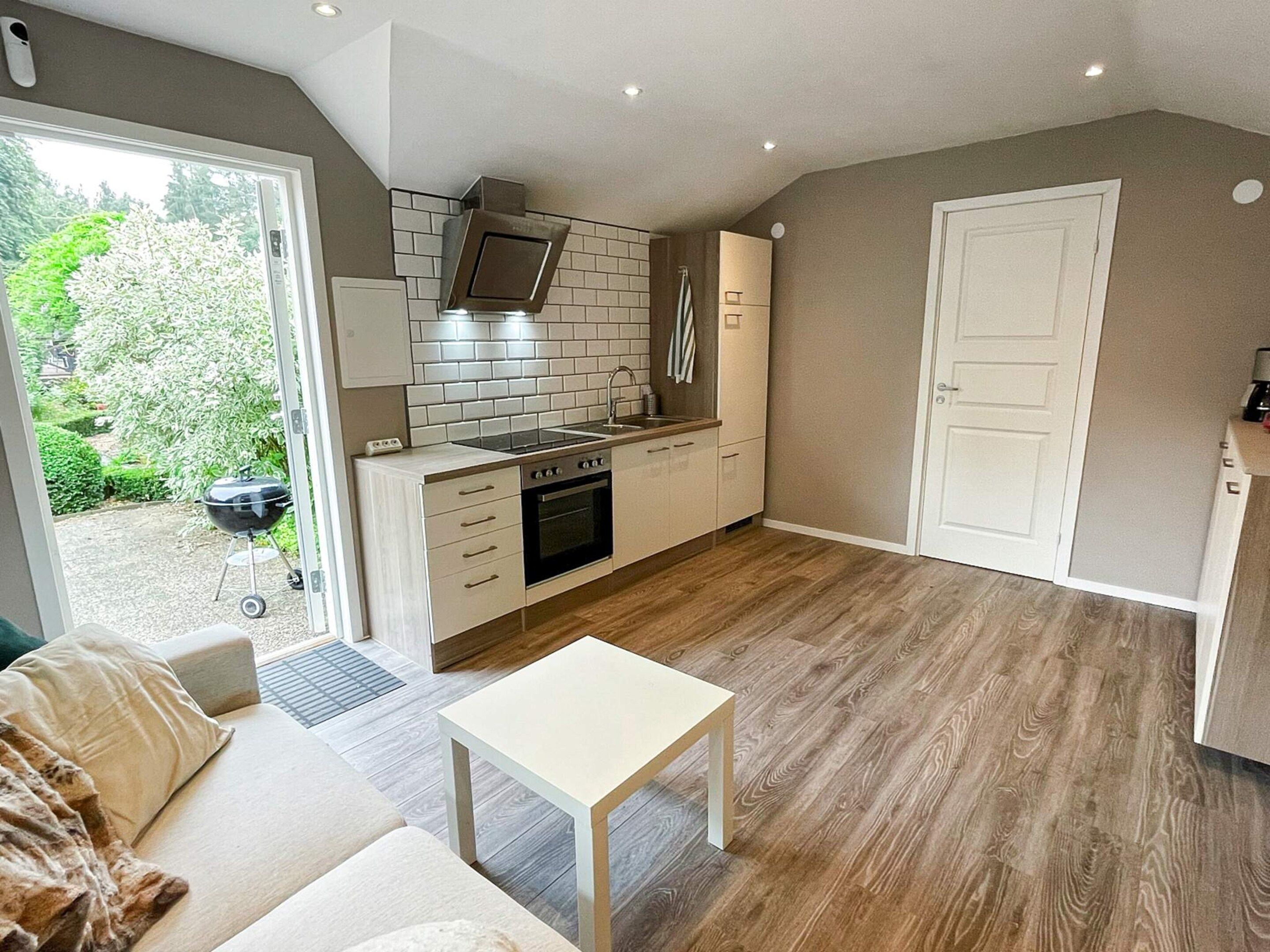 A modern kitchen with a built-in oven, a stovetop, and a microwave. There is a dining area with a table and chairs.