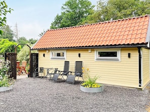 A yellow building with a red-tiled roof, two windows, and a gravel driveway. - 4 Star Holiday Home in Farlov (Färlöv)