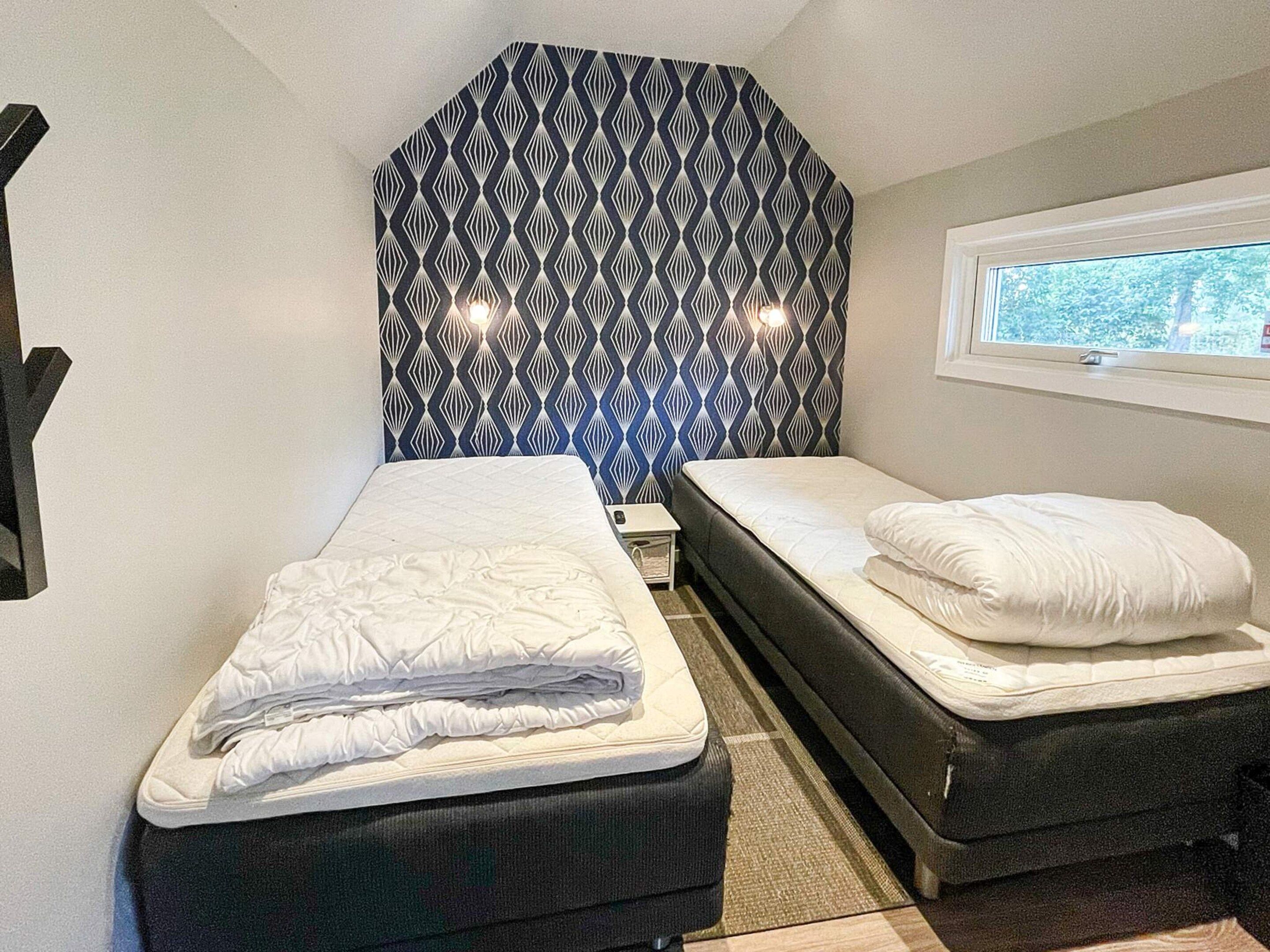 A bedroom with two beds, a window, and a patterned headboard.