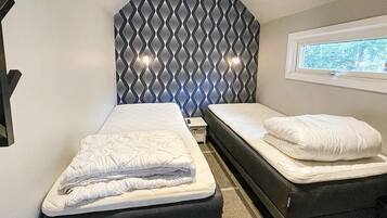 A bedroom with two beds, a window, and a patterned headboard.