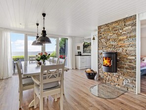 A modern interior with a dining area, a stone fireplace, and a view of the outdoors.