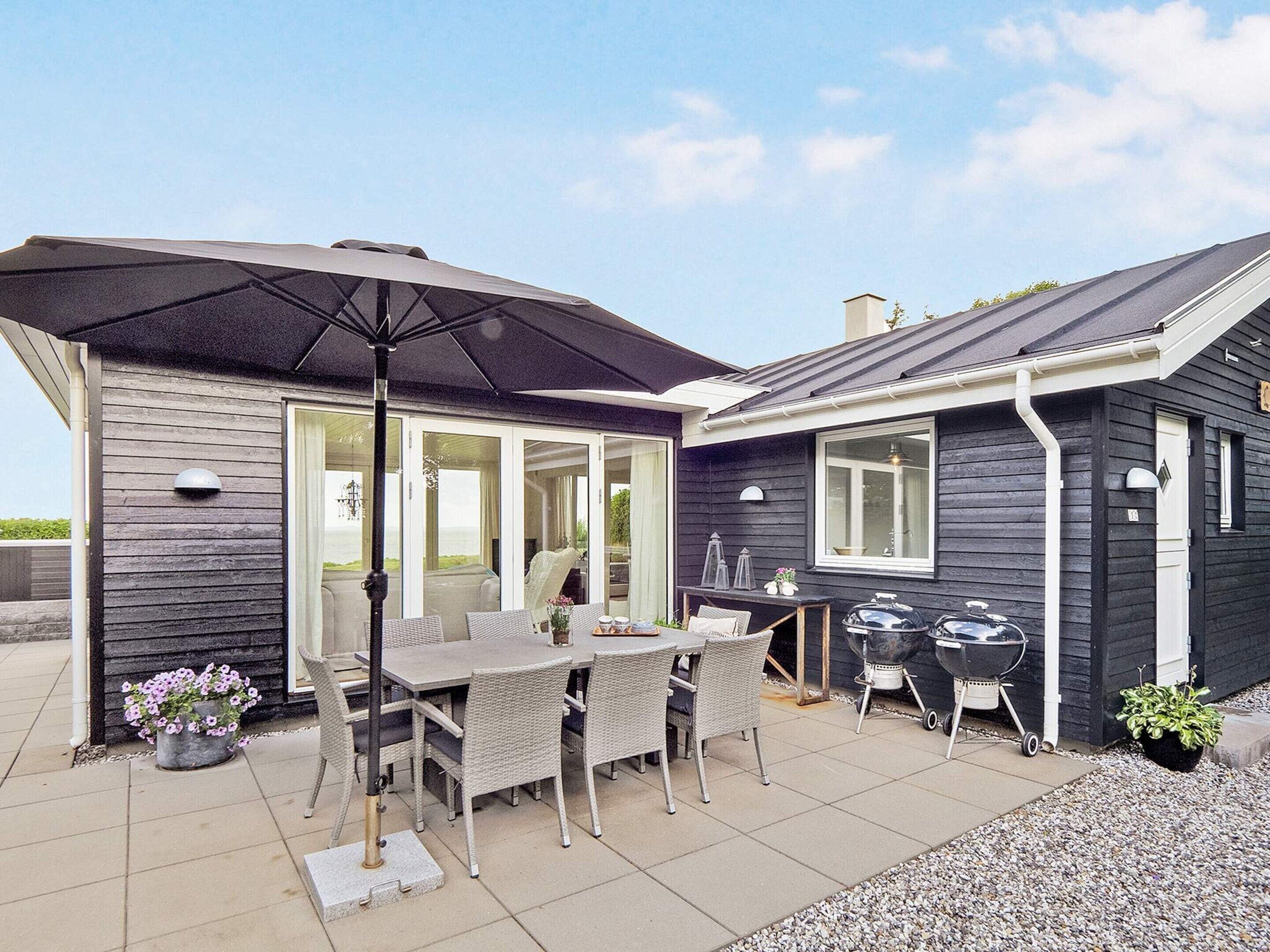 An outdoor patio with a table and chairs, a barbecue grill, and a covered seating area.