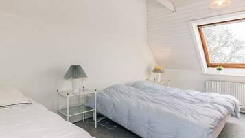 A bedroom with two beds, a window, and a radiator.