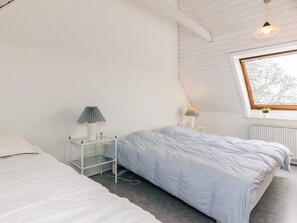A bedroom with two beds, a window, and a radiator. - 4 Star Holiday Home in Aabybro (Aabybro)