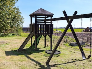 A wooden swing set with a slide and a small shelter. - 4 Star Holiday Home in Aabybro (Aabybro)