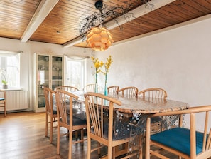 A dining area with a round table, six wooden chairs, and a hanging light fixture.
