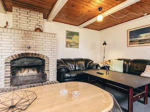 A cozy living room with a brick fireplace, leather sofas, a wooden coffee table, and a painting on the wall. - 4 Star Holiday Home in Aabybro (Aabybro)