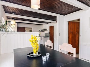 A modern kitchen with white cabinets, a wooden ceiling, and a dining area with a black table and chairs. - 4 Star Holiday Home in Aabybro (Aabybro)