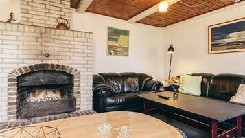 Un salón acogedor con una chimenea de ladrillo, sofás de cuero, una mesa de centro de madera y un cuadro en la pared.