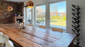 A wooden dining table with chairs, a brick wall, and a wine rack. - 6 Person Holiday Home in Torslanda-by Traum (Torslanda)