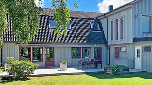 A two-story house with a tiled roof, a covered patio, and a well-maintained lawn. - 6 Person Holiday Home in Torslanda-by Traum (Torslanda)