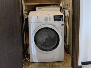 A front-loading washing machine in a laundry room with a wooden floor and a white wall. - 4 Star Holiday Home in Hammaro (Hammaro)