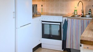Cocina compacta con estufa blanca, lavamanos y salpicadero a rayas.