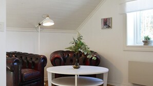 Una habitación con una mesa redonda blanca, un sofá de cuero, una lámpara de pie y una ventana con vistas.
