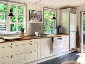 A kitchen with white cabinets, a sink, a countertop, and a refrigerator. - 4 Star Holiday Home in Vejby (Vejby)