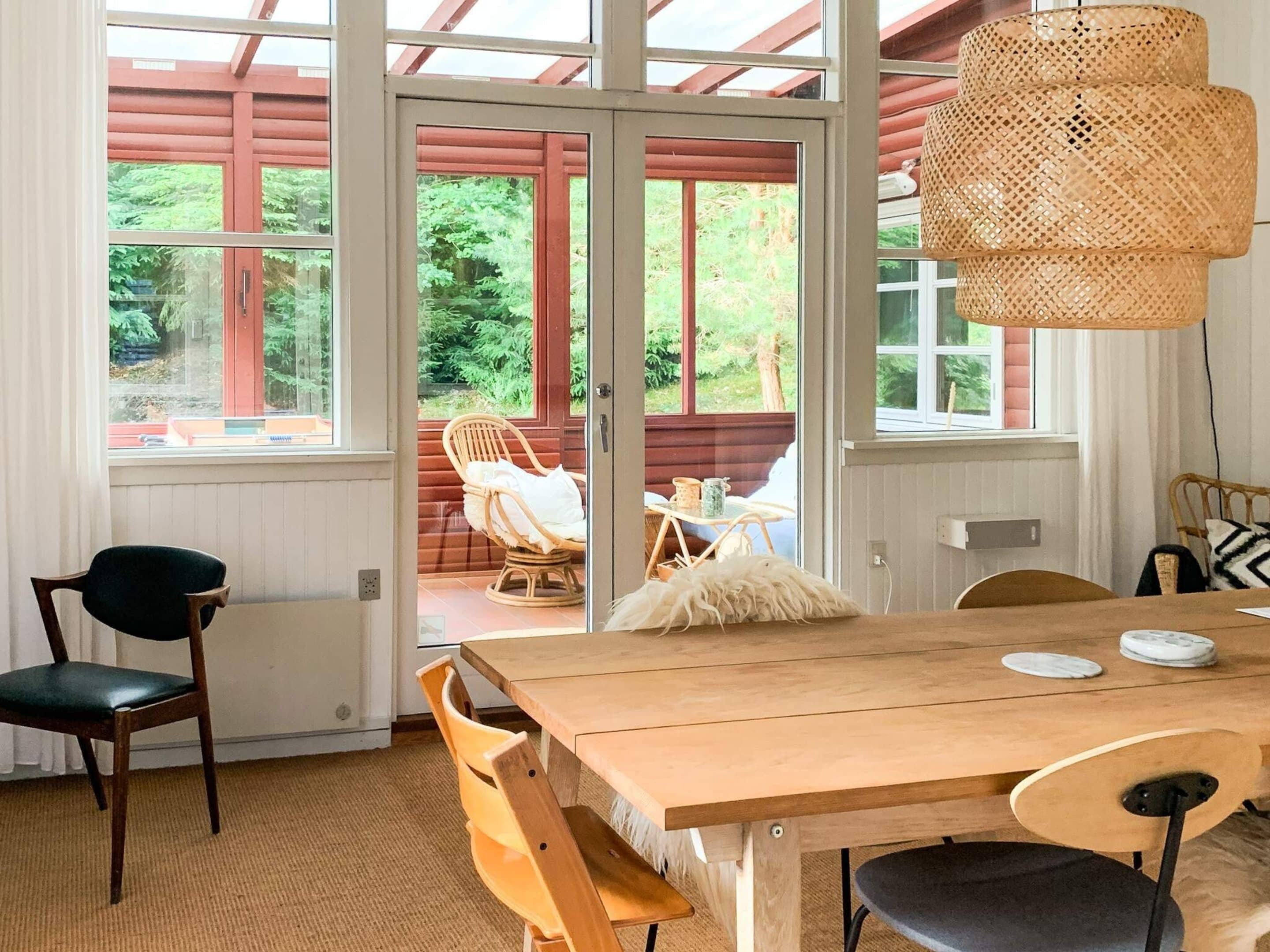 A dining area with a wooden table, chairs, and a wicker pendant light.