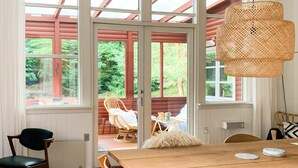 A dining area with a wooden table, chairs, and a wicker pendant light.