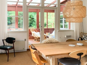 A dining area with a wooden table, chairs, and a wicker pendant light.