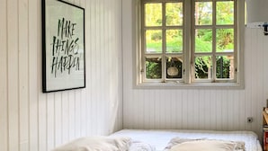 Una stanza con un letto, una citazione motivazionale incorniciata e una finestra vista verde.