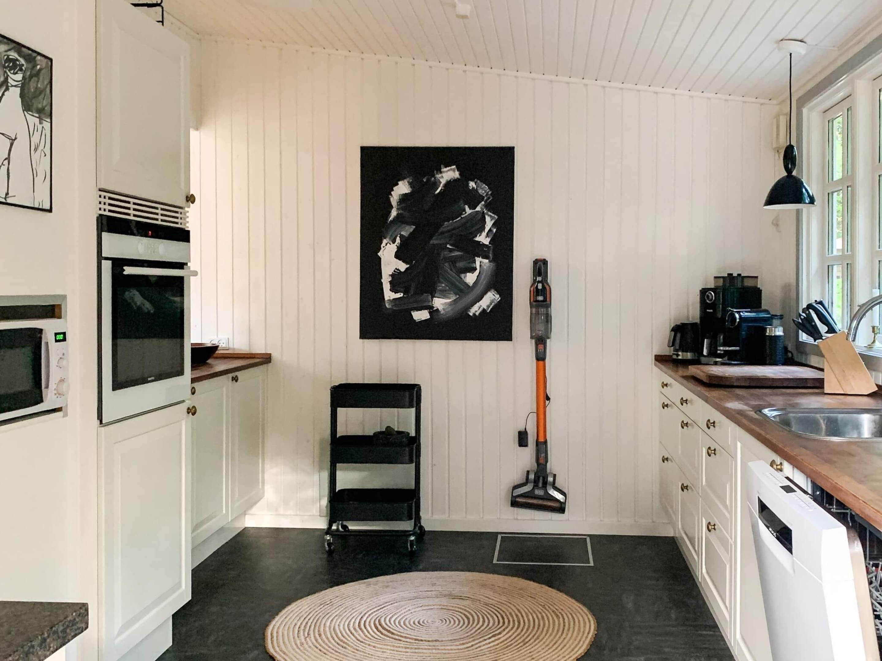 Een keuken met een magnetron, oven, spoelbak en een stofzuiger.