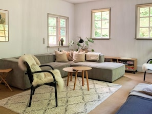 A living room with a grey sofa, a white chair, a small round table, and a bookshelf.