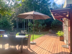 A wooden deck with a table and chairs, an umbrella, and a grill. - 4 Star Holiday Home in Vejby (Vejby)