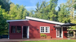 Una baita di legno rossa con veranda, una piccola finestra e una porta.