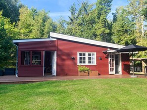 A red wooden cabin with a deck, a small window, and a door. - 4 Star Holiday Home in Vejby (Vejby)