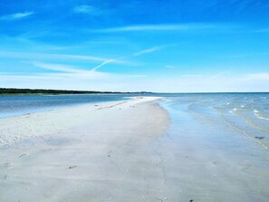 Ein Strand mit klarem Himmel und ruhigem Wasser.