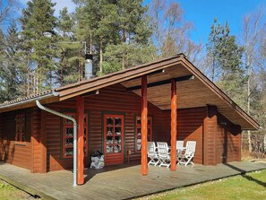 A wooden cabin with a porch, a chimney, and a small deck with chairs. - 6 Person Holiday Home in Hadsund (Hadsund)