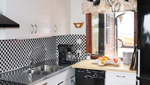 A kitchen with a black and white checkered backsplash, a coffee maker, and a fruit bowl on the counter.