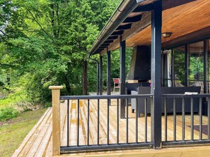 A wooden deck with a covered seating area, a grill, and a view of the surrounding greenery. - 4 Star Holiday Home in Knared (Knared)