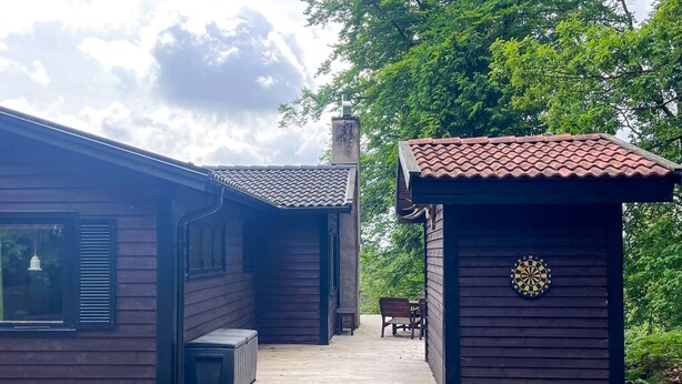 A wooden cabin with a porch and a small shed.
