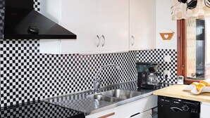 A kitchen with a black and white checkered backsplash, stainless steel appliances, and a coffee maker.