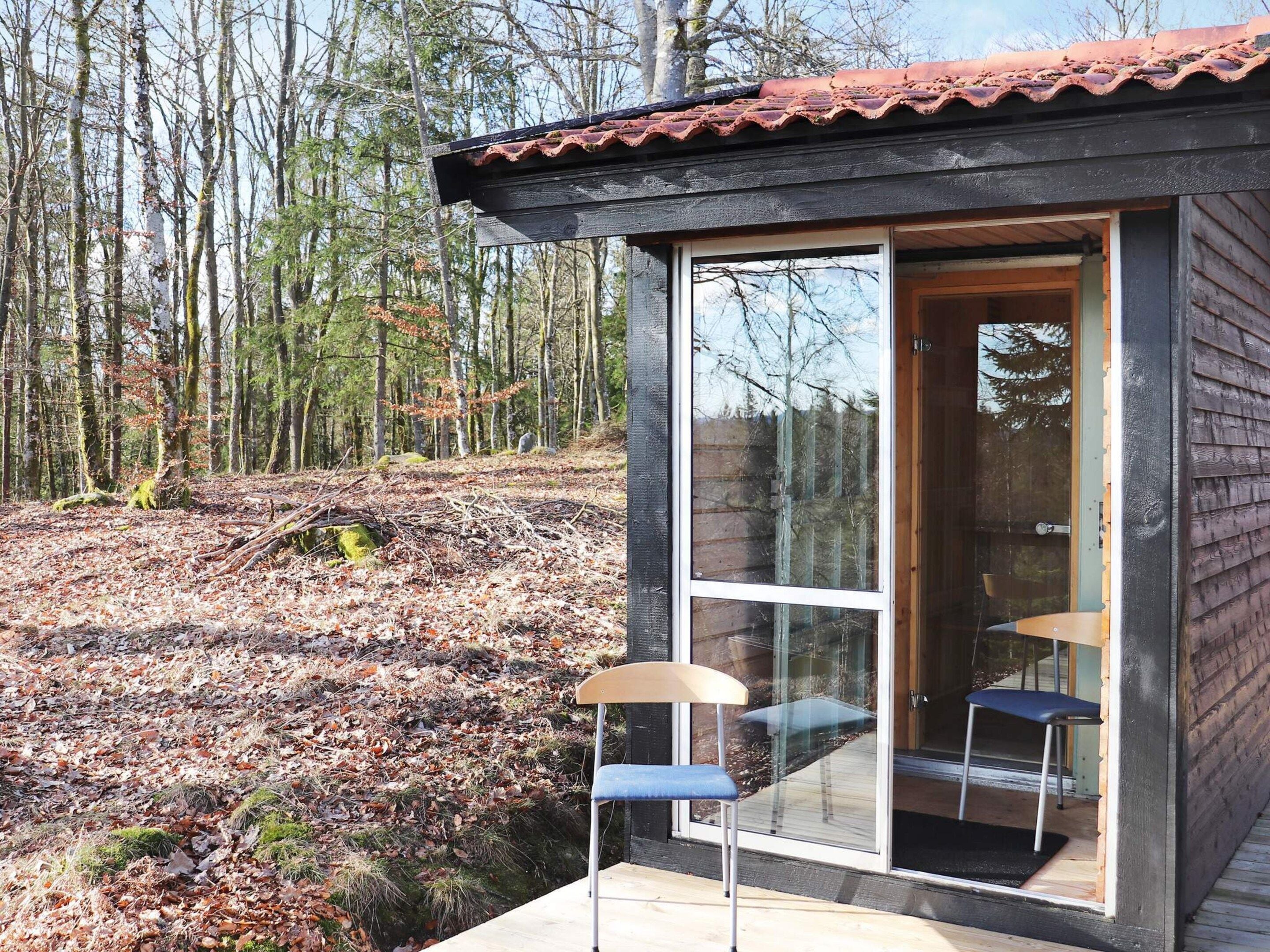A small wooden cabin with a glass door and two chairs outside.
