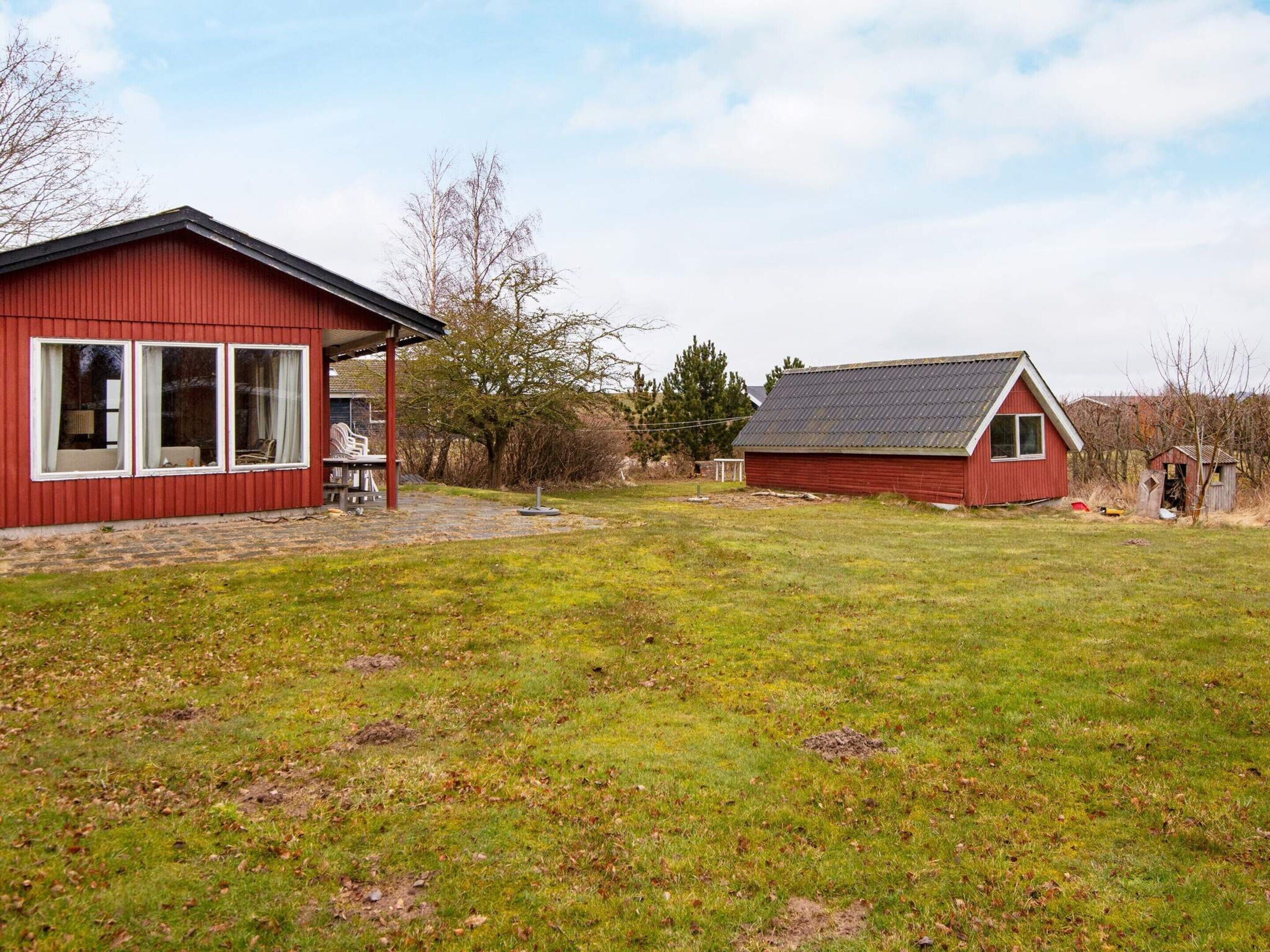 A red building with a covered patio and a smaller adjacent structure.
