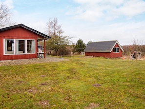 Un bâtiment rouge doté d’un patio couvert et d’une petite structure adjacente.